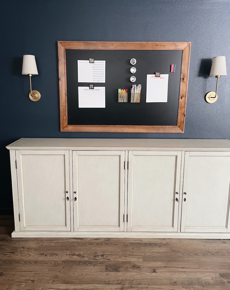 https://theinspiredroom.net/wp-content/uploads/2021/11/hale-navy-blue-walls-chalkboard-brass-sconces-linen-shades-double-door-console-cabinet-the-inspired-room.jpg