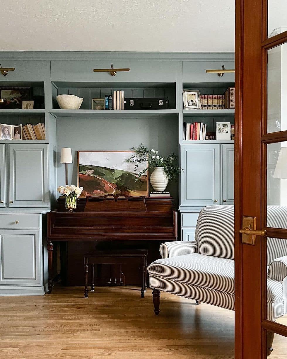 https://theinspiredroom.net/wp-content/uploads/2023/03/wood-piano-blue-gray-built-in-cabinets-living-room-striped-chair.jpg