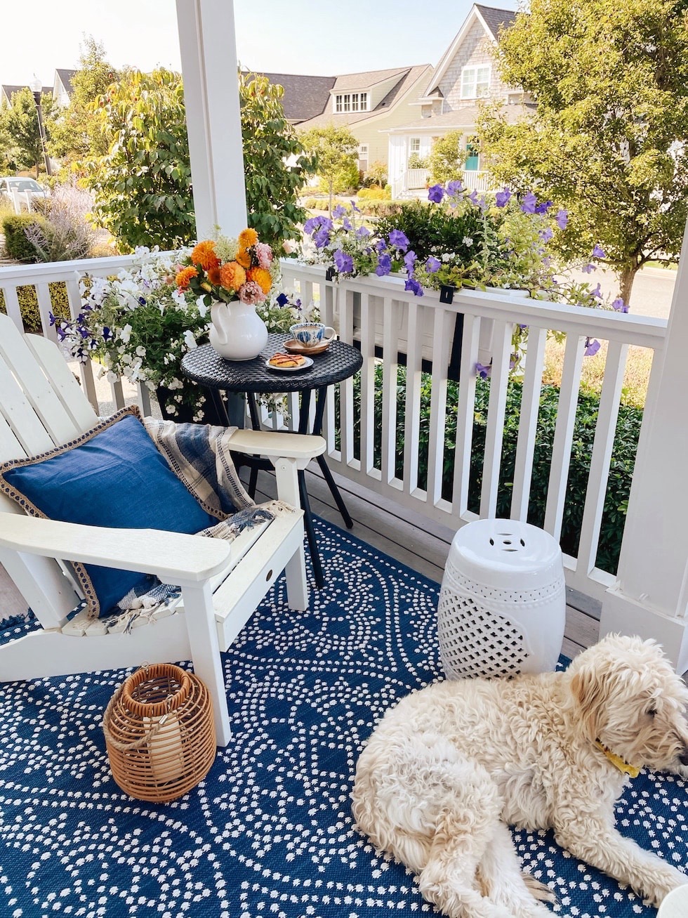 https://theinspiredroom.net/wp-content/uploads/2023/05/front-covered-porch-adirondack-chair-blue-white-rug-cafe-table-inspired-room.jpg